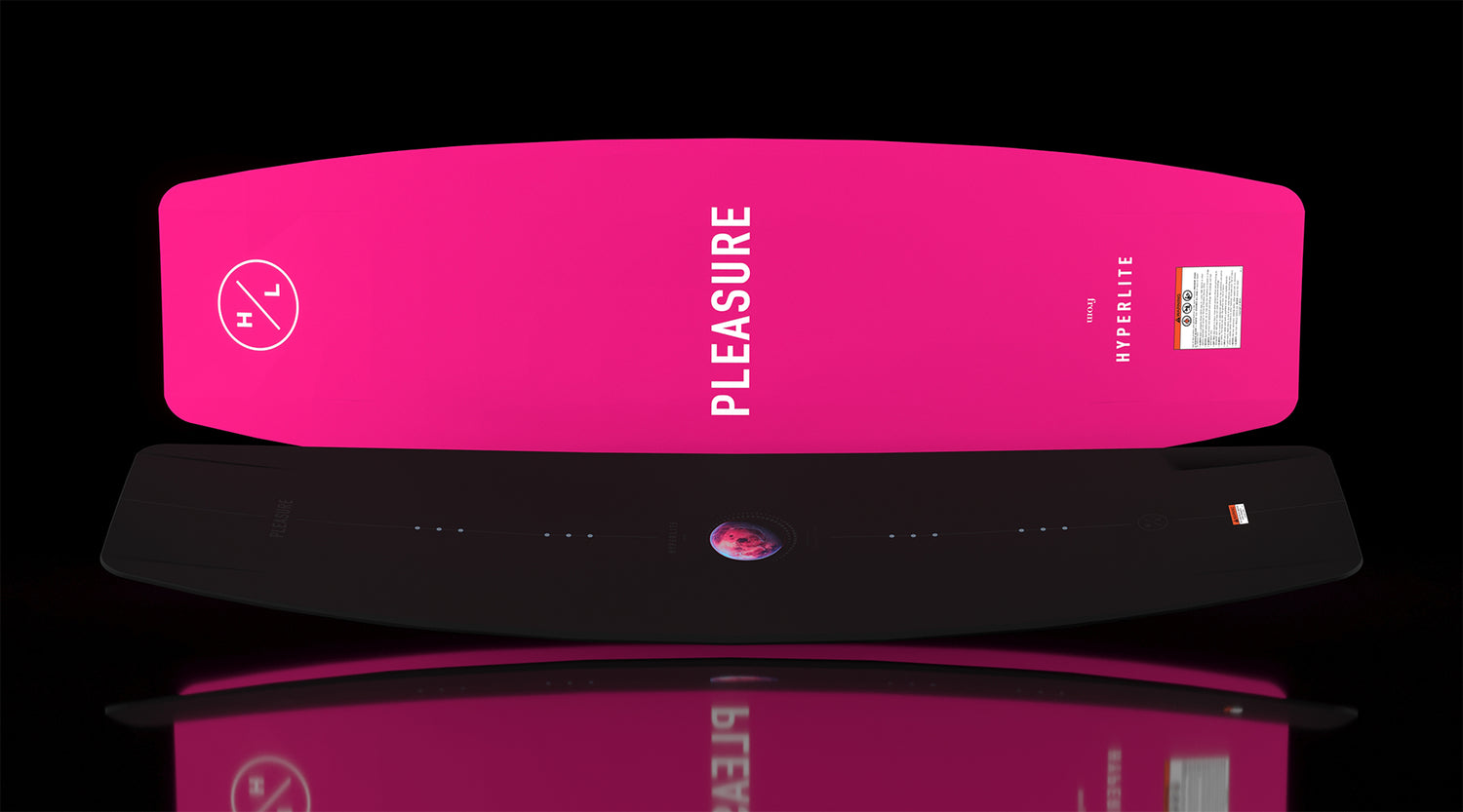 Flat display of Pleasure wakeboard with black top and pink base featuring logo text.