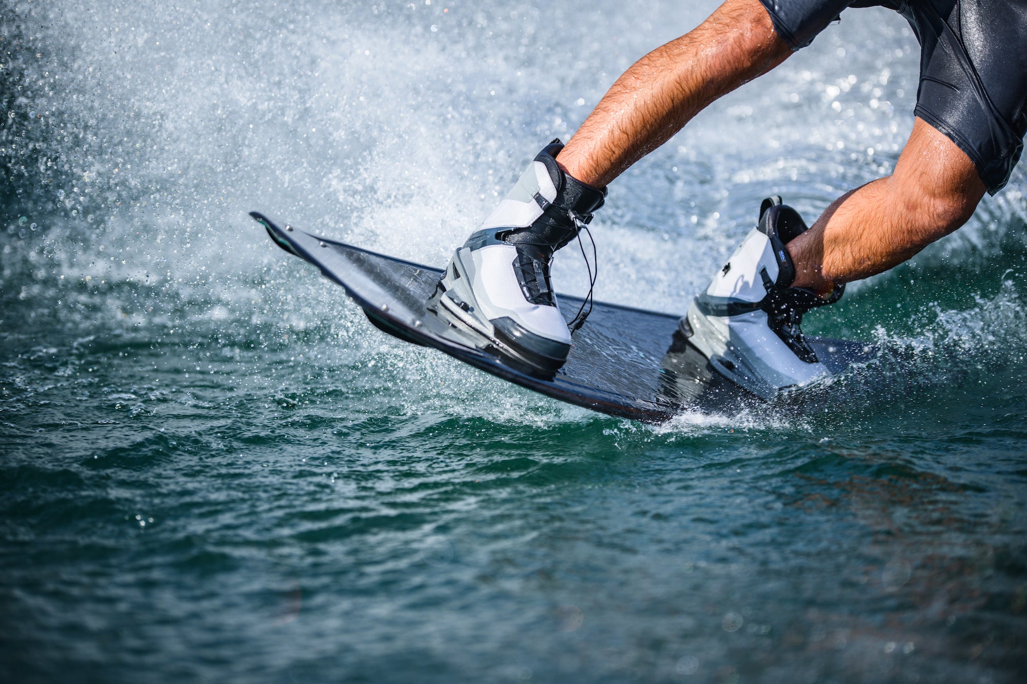 Close-up of a person wakeboarding, water splashing around the board.
