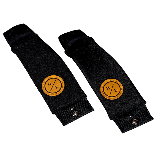 Angled view of two black neoprene foil board foot straps with tan HL logo patches.