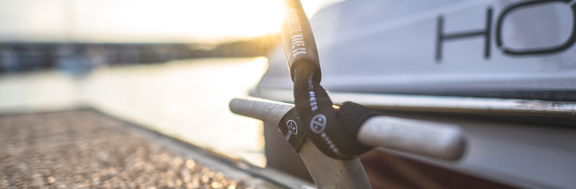 Docked boat tied to a railing with a rope, sunlight reflecting on the water.