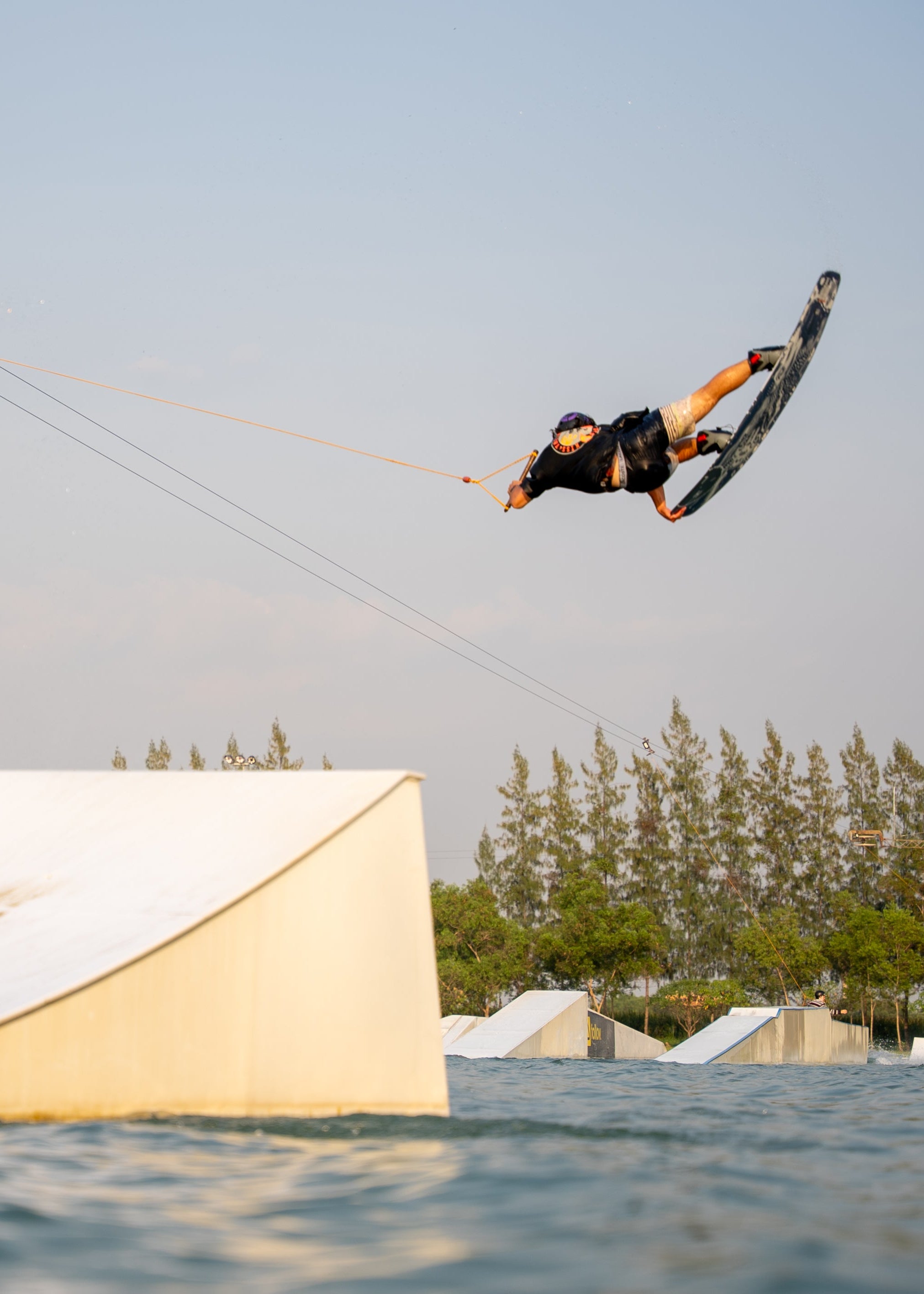 Person wakeboarding mid-air with a vivid blue sky in the background.