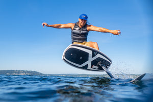 A person on a Starship w/Raptor 1100 rides over water in a blue cap on a sunny day.