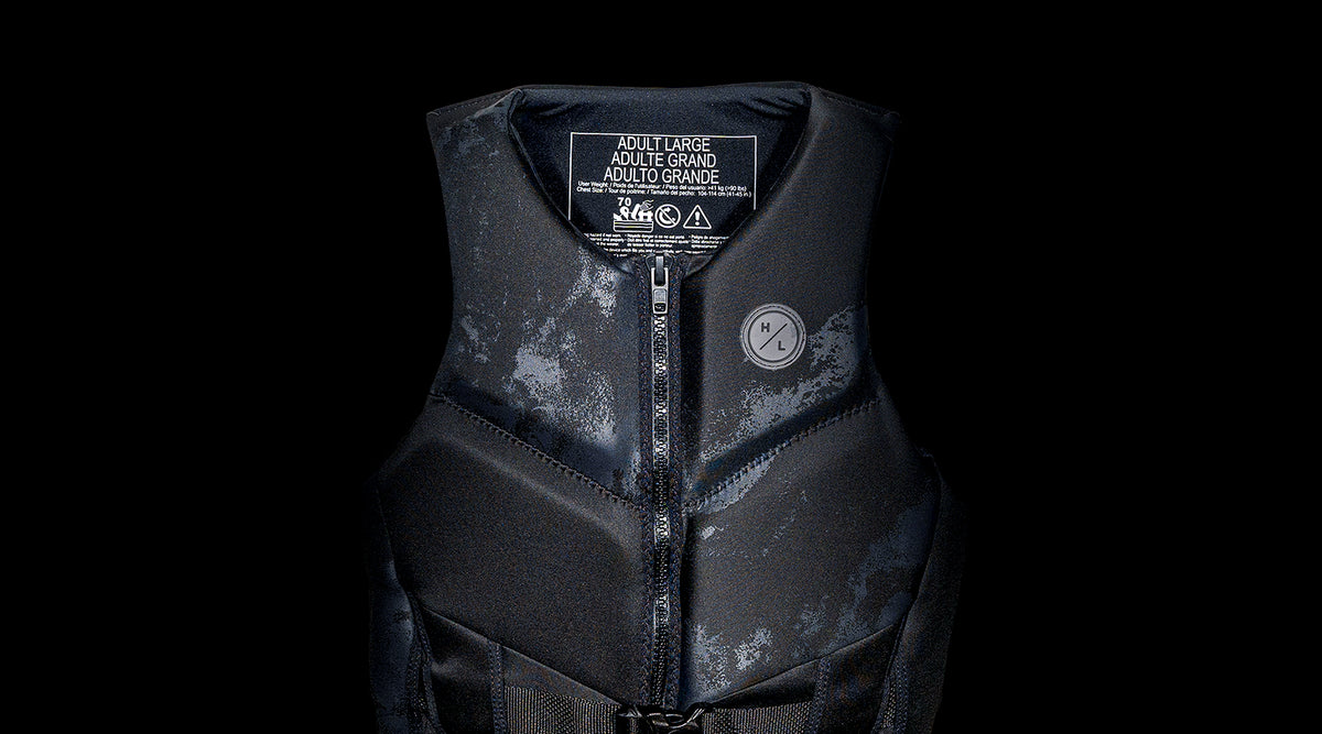 Black life vest in a dark setting, size label Adult Large visible inside.