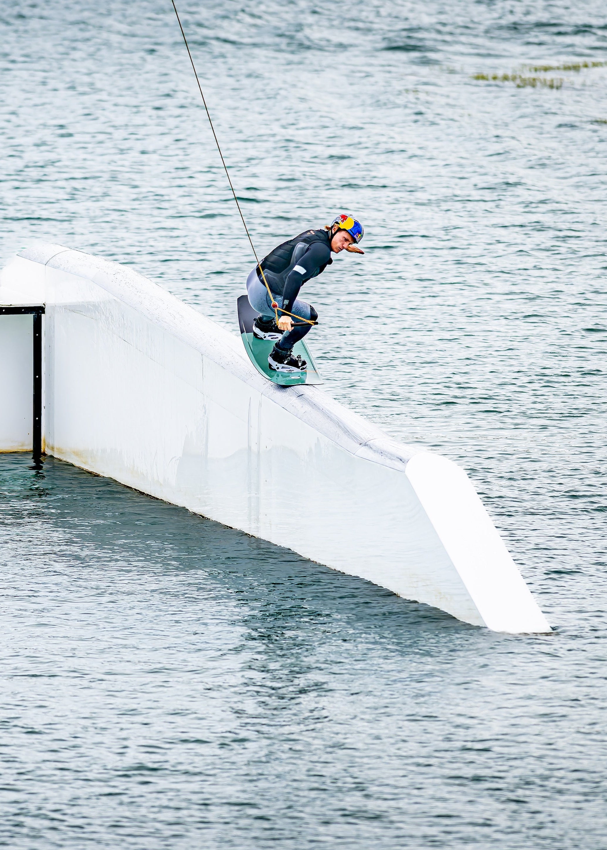 Person wakeboarding on a rail obstacle in a body of water.