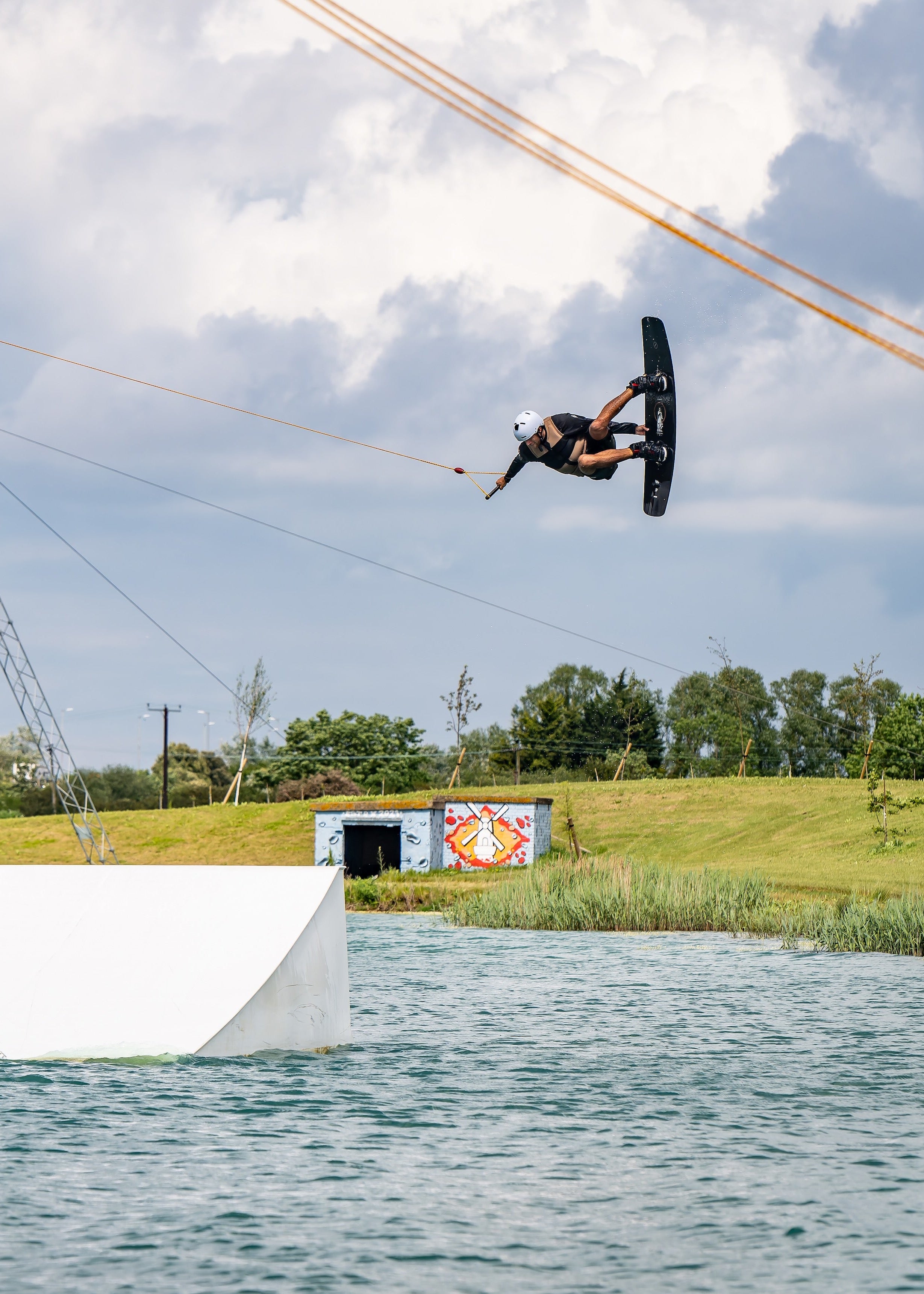 Person wakeboarding, performing an aerial trick in a scenic outdoor setting.