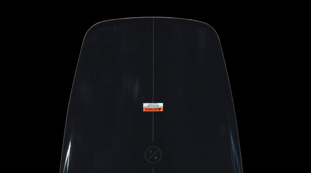 Detail view of the Pleasure wakeboard tail with logo circle and warning label.