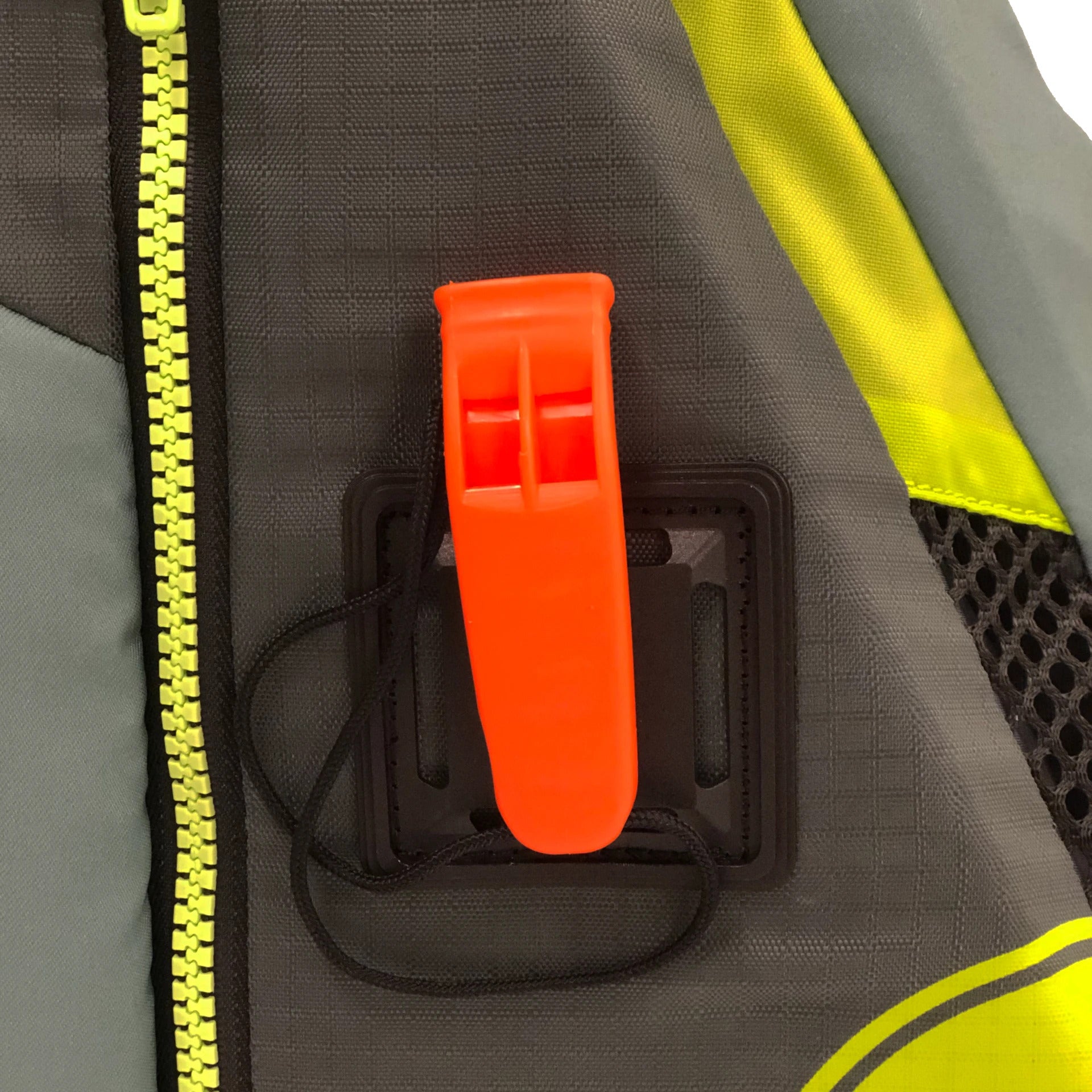 Close-up of a bright orange whistle attached to a gray and yellow fabric surface.