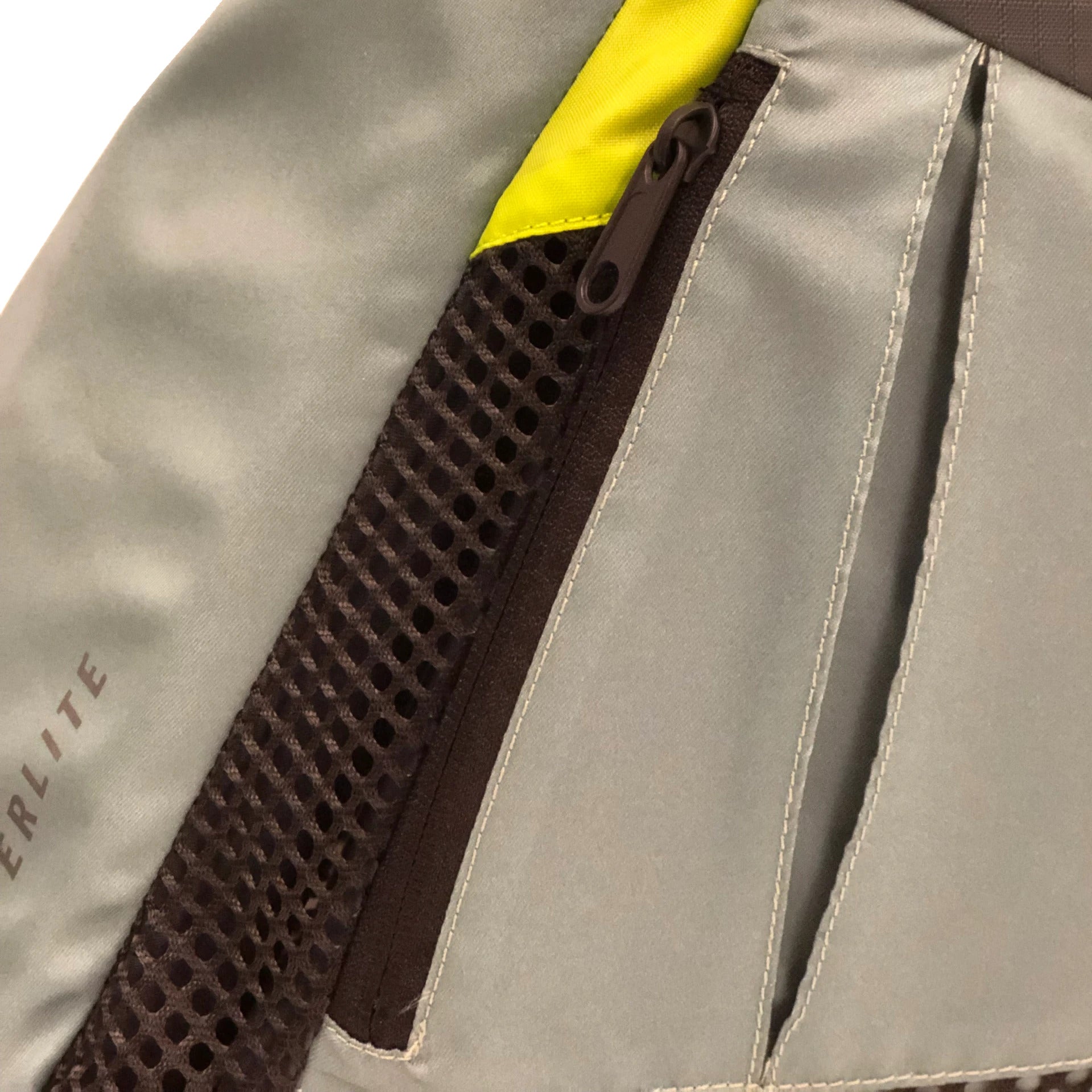 Green and yellow fabric backpack with mesh pocket and zipper.