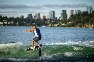 A city skyline frames a person gliding on a Starship w/Raptor 1100 Foil Kit.