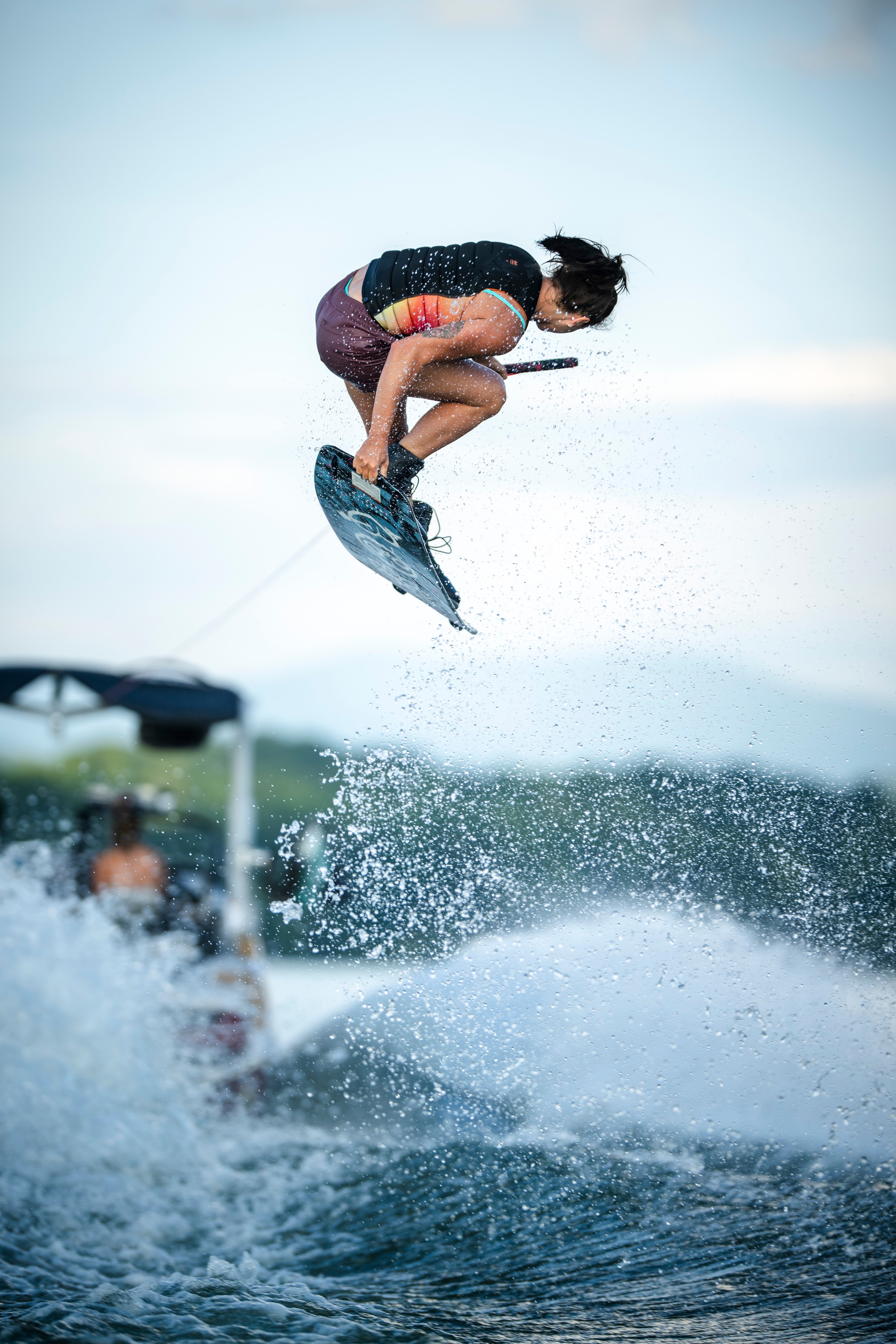 Person wakeboarding, mid-air jump with splashing water.