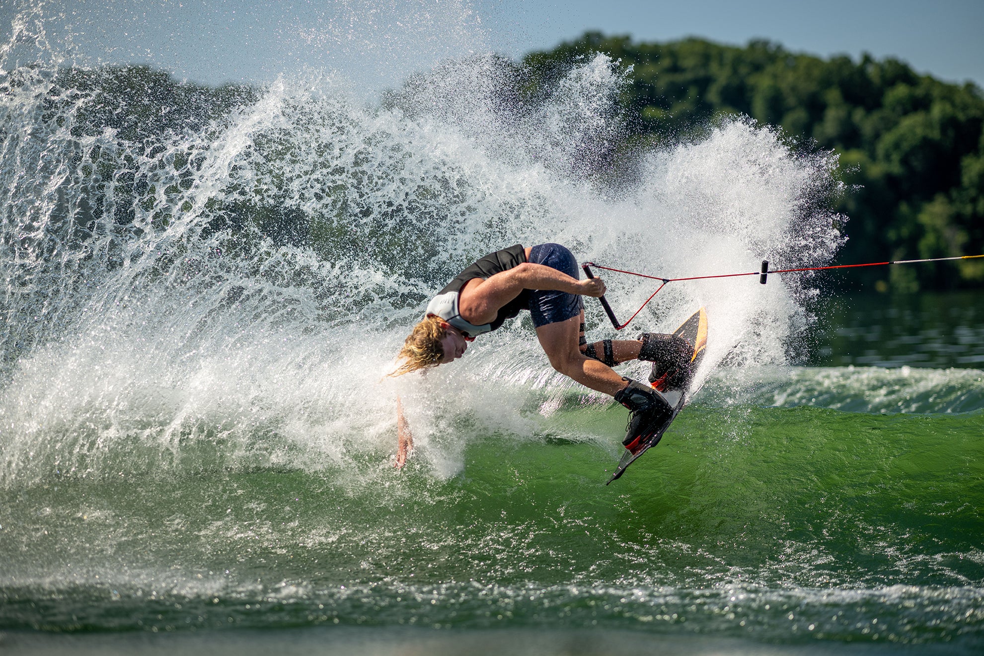 Person wakeboarding, performing a trick on a lake with splashing water.