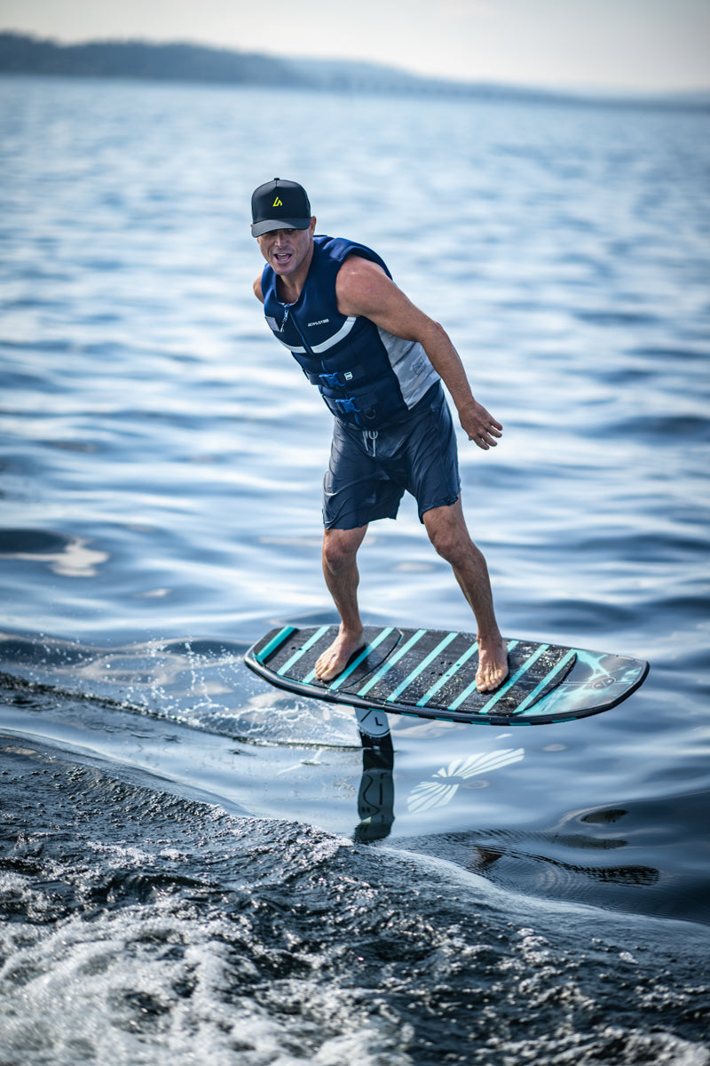 Rider glides on a Shuttle w/Falcon Foil Kit, wearing a life vest and cap.