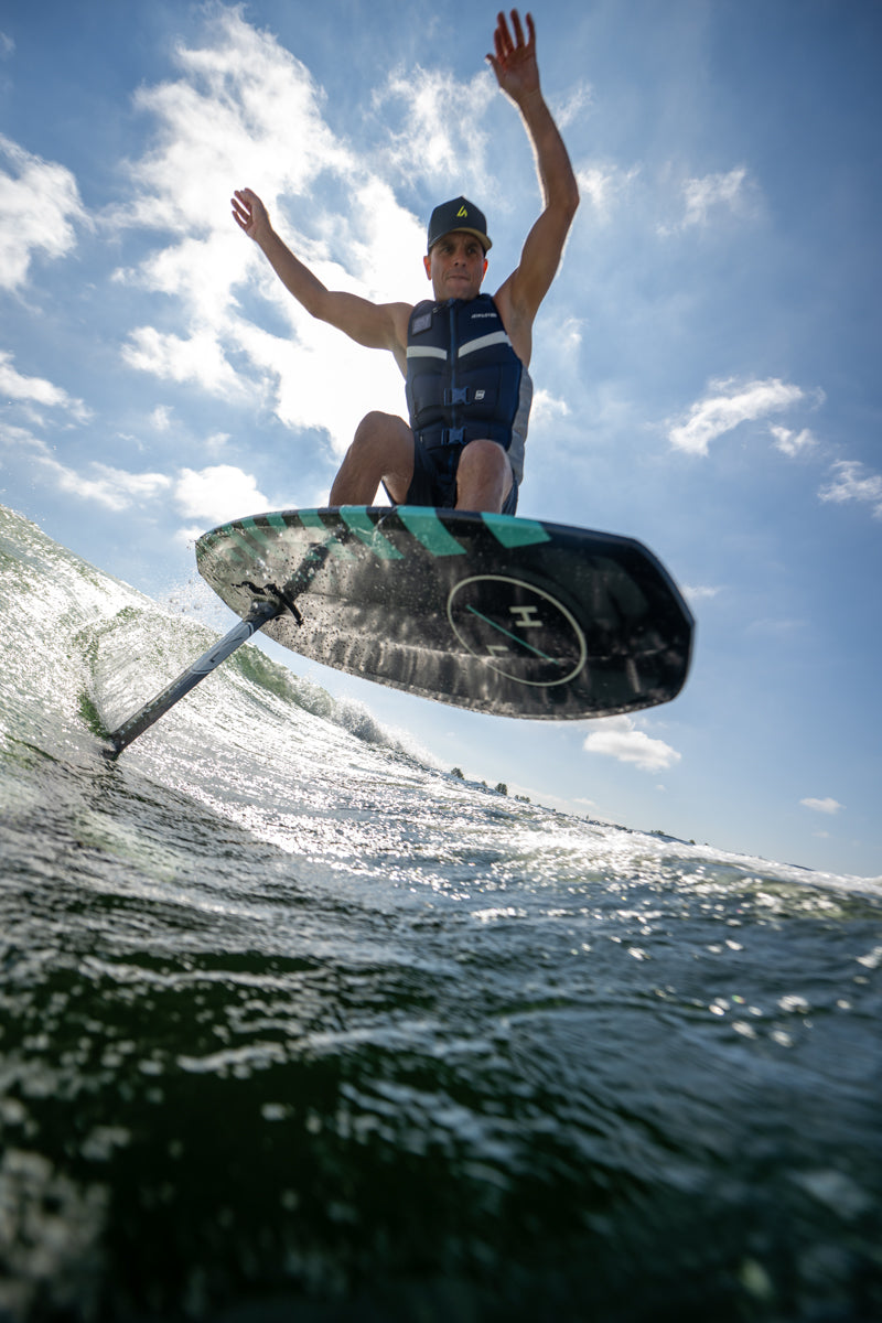 Shaun Murray e-foiling a wave on Shuttle w/Falcon Foil Kit, wearing a life vest and cap.
