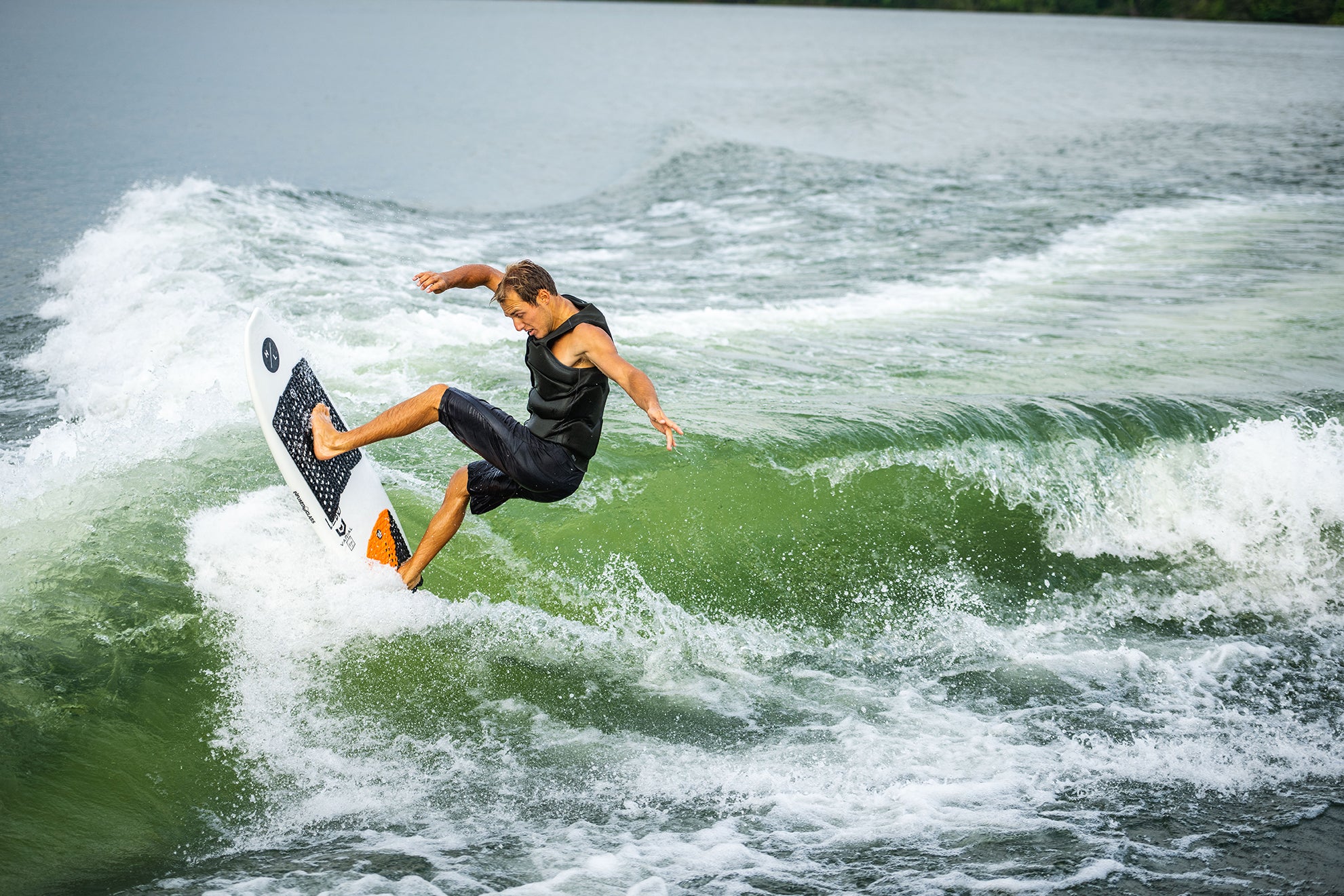 Person surfing on a wave, performing a trick on a sunny day.