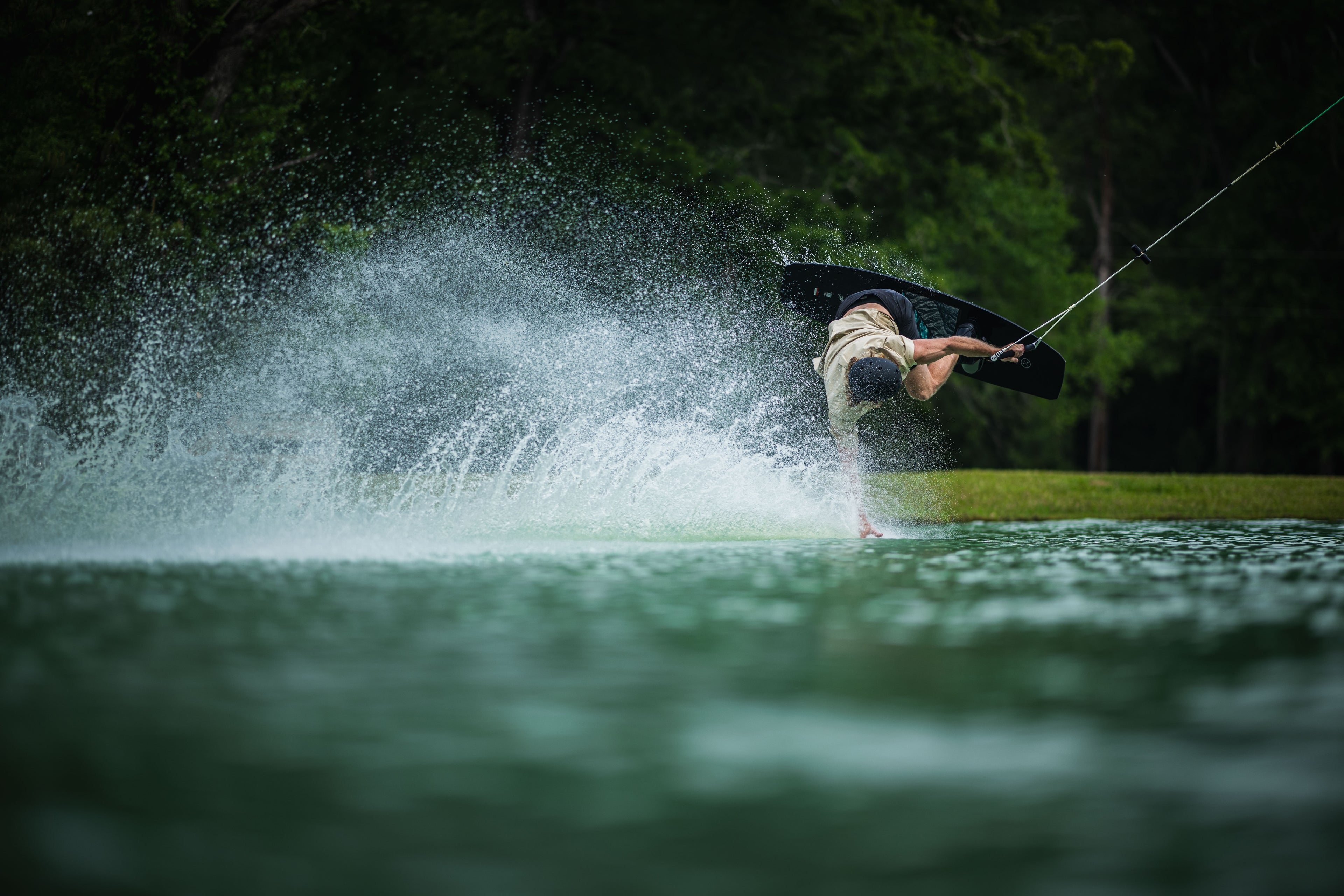 Person wakeboarding and performing a trick, splashing water.