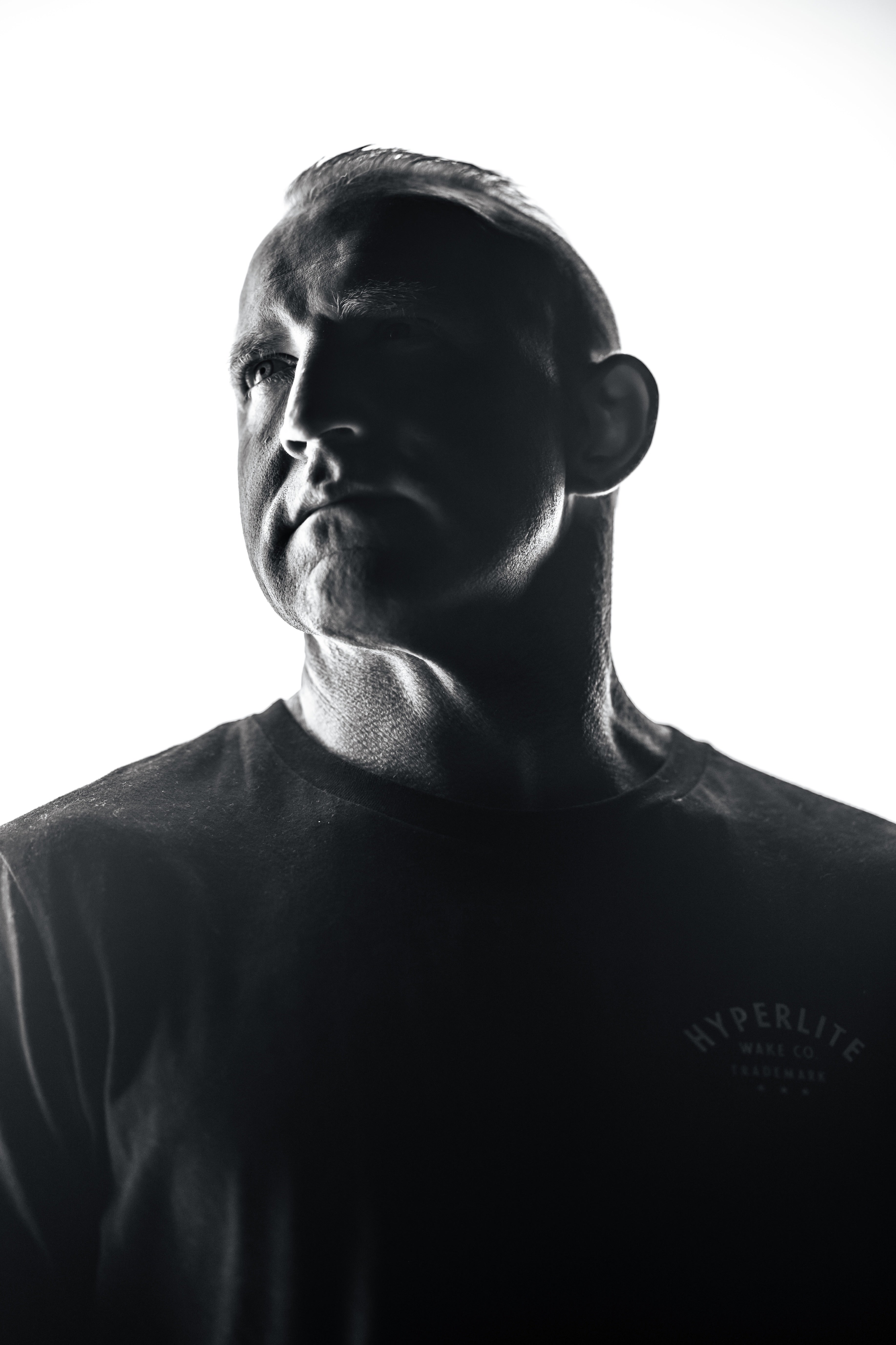 Man in a black t-shirt with side lighting on a white background.