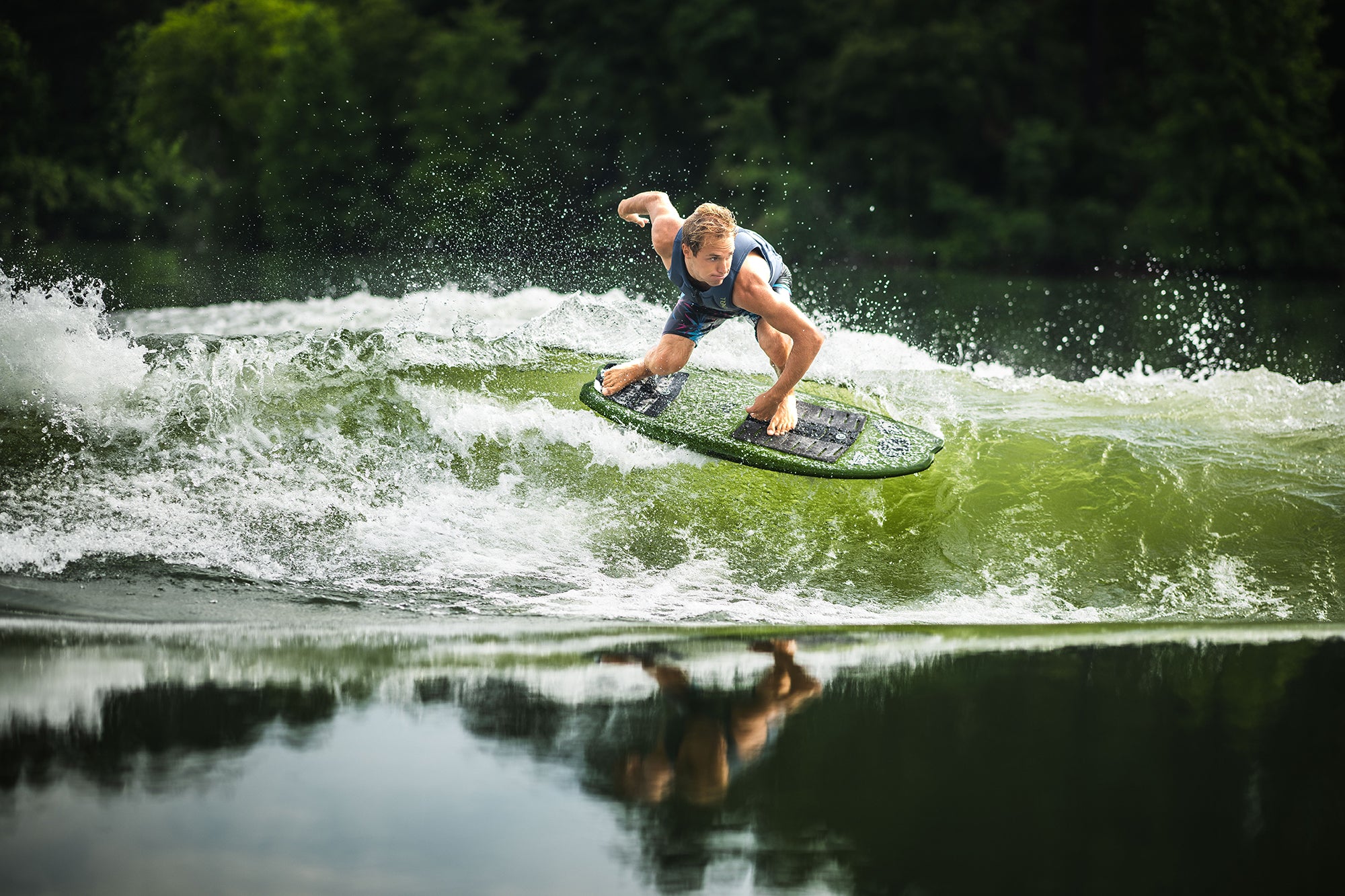 Person surfing on a green wave, surrounded by lush greenery in the background.