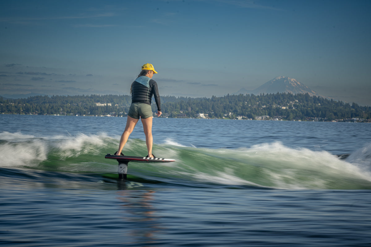 Surfing on a Majik Karpet with the MK Carbon Foil Kit, set against a mountain view.