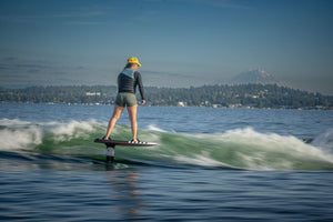 Surfing on a Majik Karpet with the MK Carbon Foil Kit, set against a mountain view.