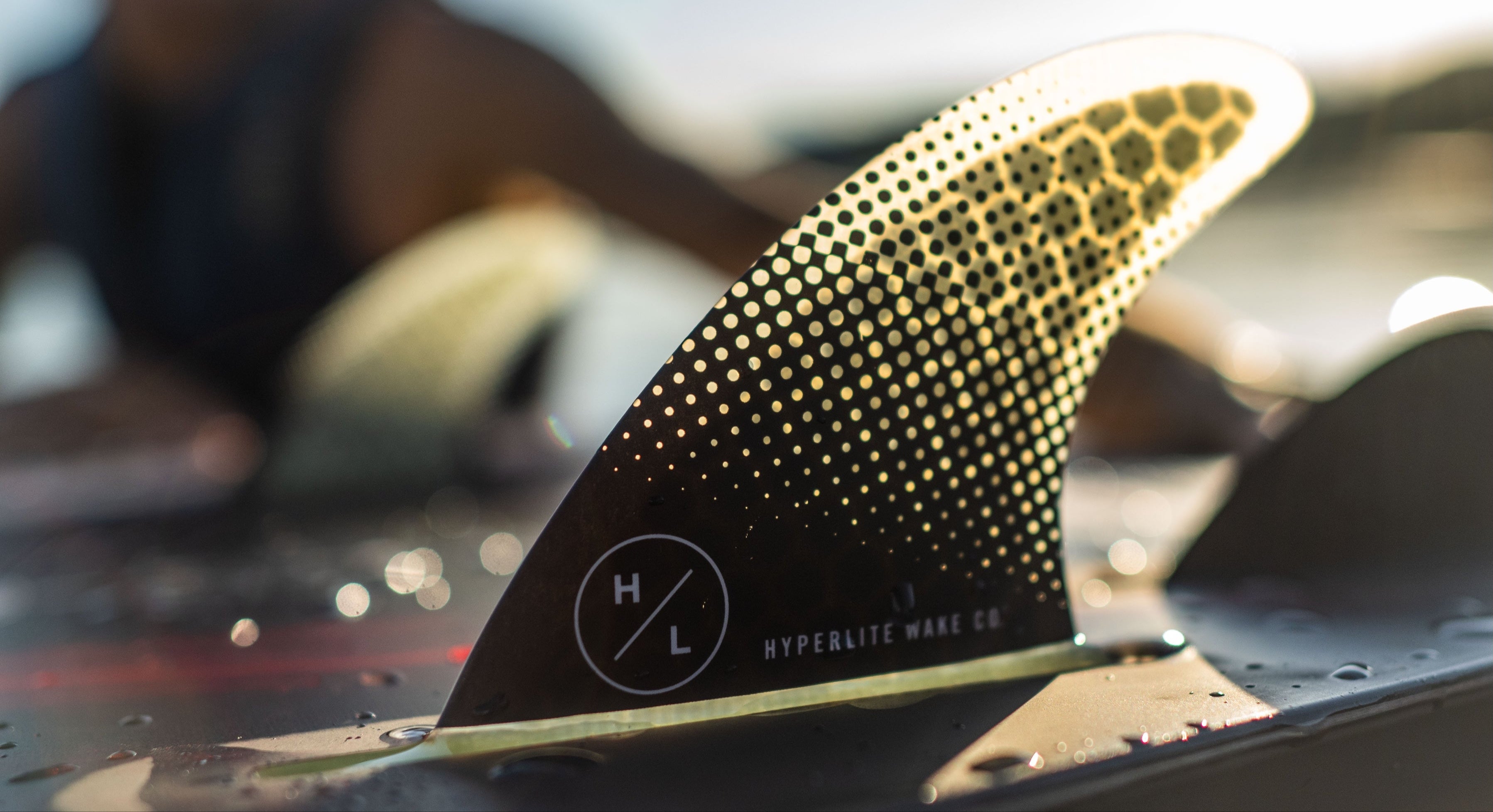 Close-up of a perforated surfboard fin with Hyperlite Wake Co. logo.
