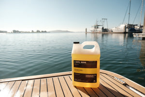 Seipel Marine EVA foam cleaner refill jug placed on a teak boat deck with marina in the background.
