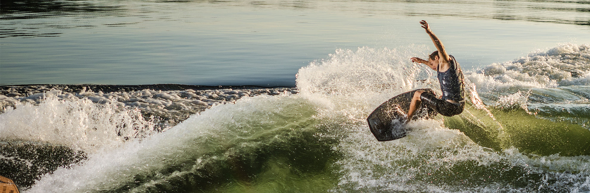 Person in action, wakesurfing on a large wave in sunny conditions.