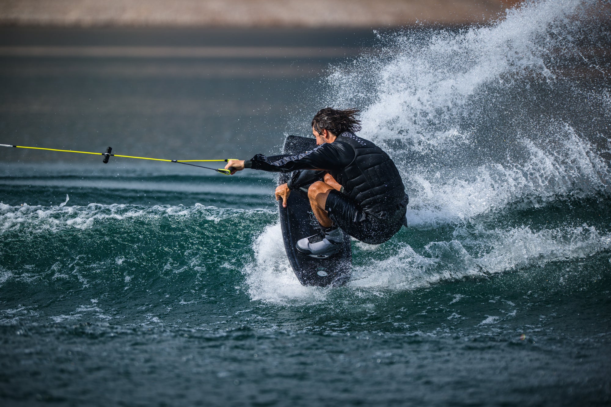 Person wakeboarding on a wave with a blurred background.